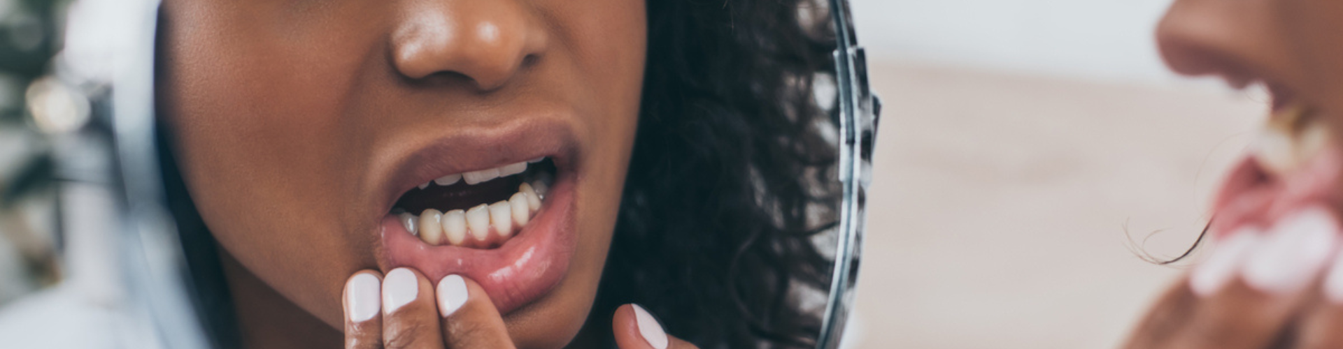 A woman looking in the mirror, checking her teeth due to pain.